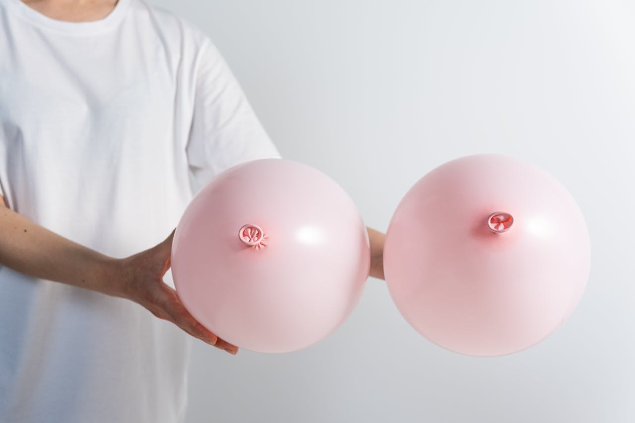 Man in White T-shirt Holding Two Pink Balloons